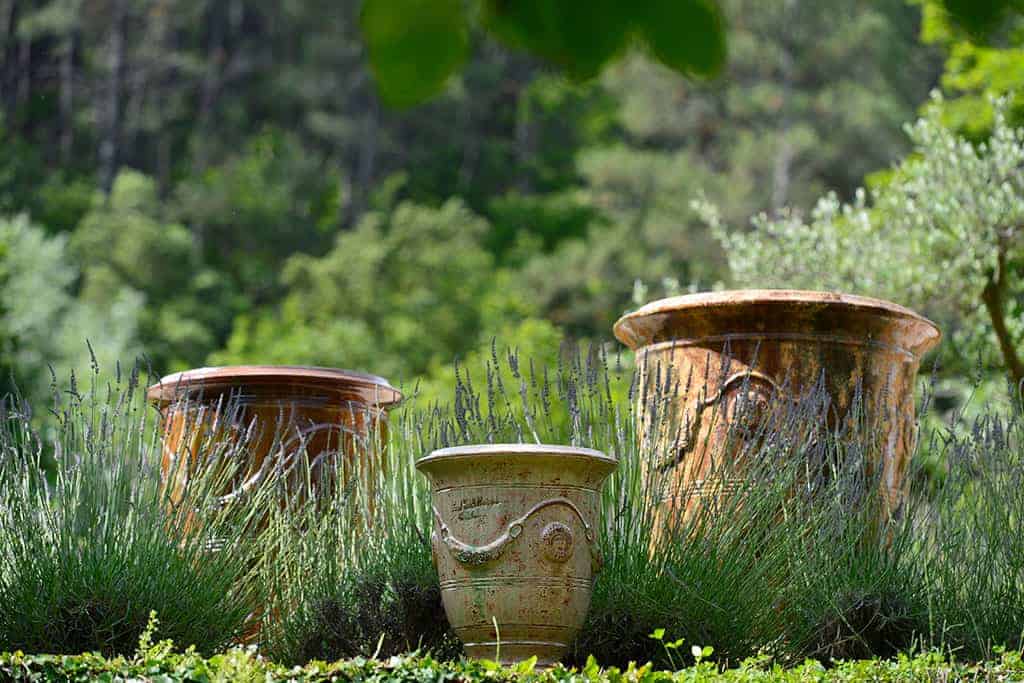 3 vases d'Anduze mis en sc&egrave;ne dans un jardin
